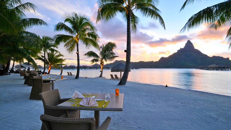 Several tables-for-two on the beach overlooking the ocean at Sands Restaurant at the InterContinental Bora Bora Resort Thalasso Spa