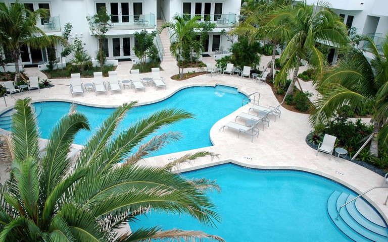 Overhead view of Santa Maria Suites' multi-pool area with lounger chairs and palm trees and other foliage