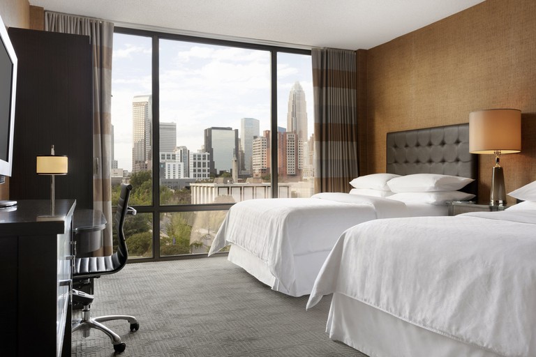 Room at the Sheraton Charlotte Hotel with two double beds and floor-to-ceiling windows with city views