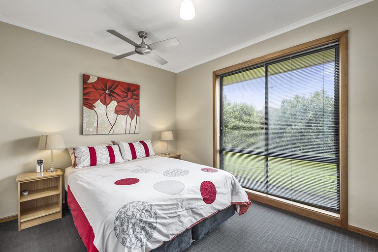 Cosy bedroom with floral artwork and large picture window facing greenery at Starline in Mount Gambier, South Australia