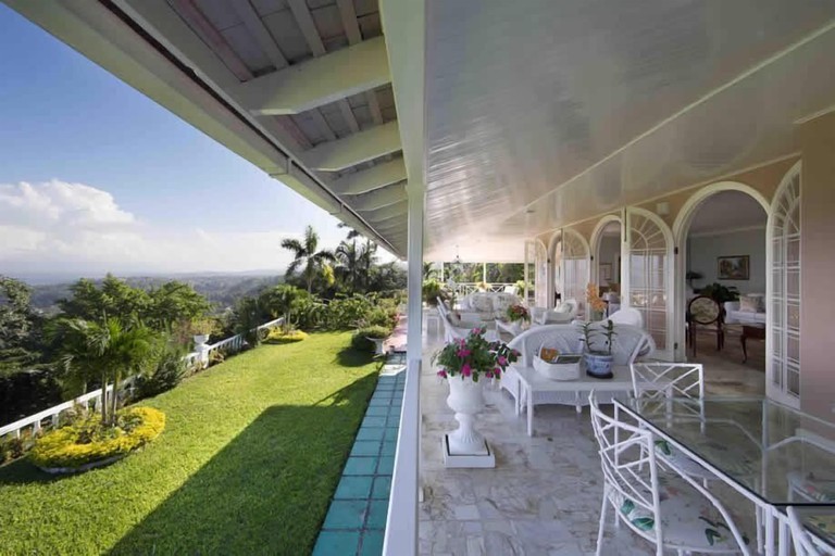 A view over hills from the lofty veranda at Stoneaway, 6BR by Jamaican Treasures; many seating options are available