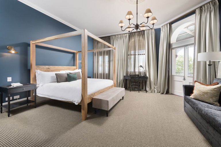 Spacious luxury king room with four-poster bed and arched windows at the National Hotel in Perth