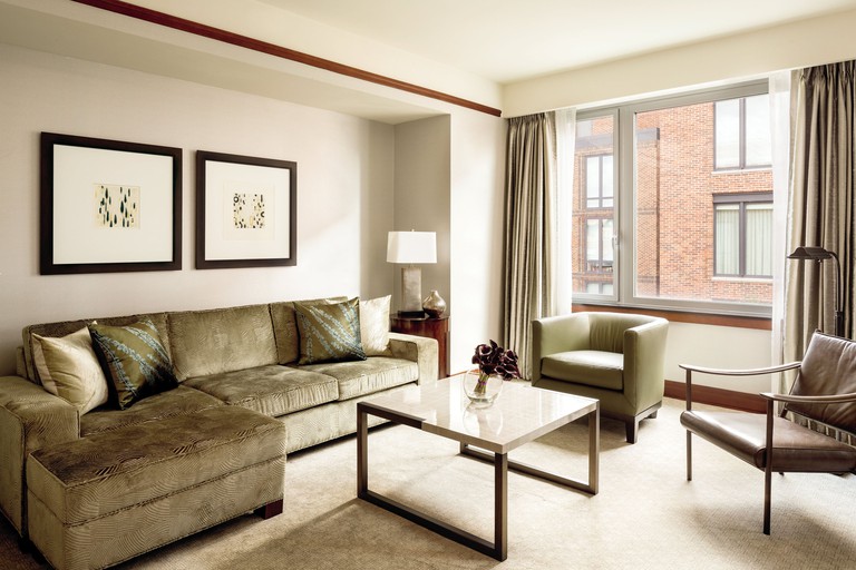 A cosy and stylish room at The Ritz-Carlton, Washington, D.C, with a sofa, coffee table, two chairs, two lamps, a small side table and modern decor.