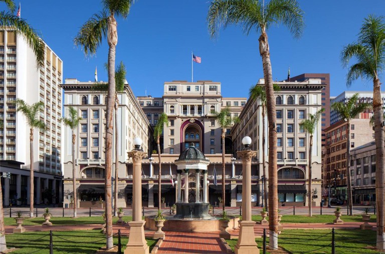 Imposing exterior of the US GRANT, a Luxury Collection Hotel, with a fountain in front and an American flag on top