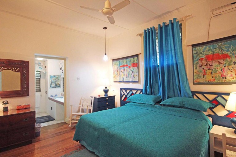 Bedroom at the White Cap, Barbados, with a double bed with turquoise bedding and blue curtains