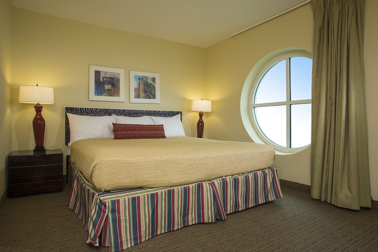 A double room at Seaside Resort has classic coastal design, with striped bed, a circular window and tall lamps