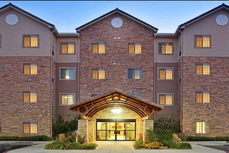 Exterior of stone-facade building and arch entrance to Staybridge Suites Las Cruces