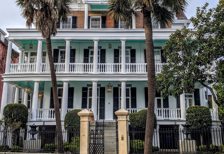 Front entrance to the Battery Carriage House in classic grand southern style with columns, balconies and palm trees