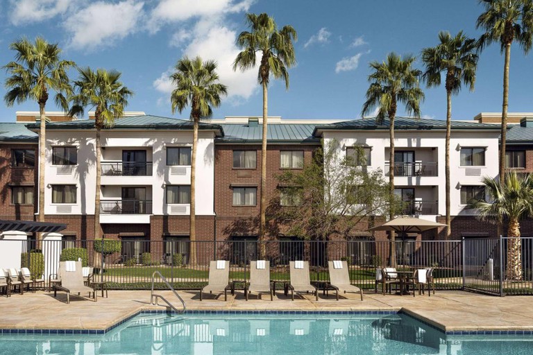 A swimming pool with tall trees and the exterior of Sonesta Select Tempe Downtown