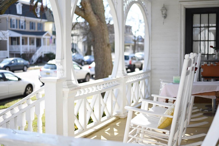 A white porch with white-painted wooden rocking chairs at Ocean City Mansion
