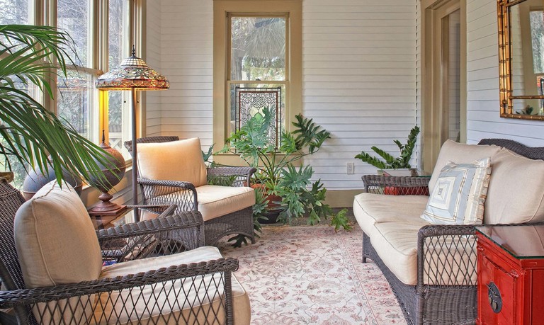 Rattan seating with cushions and potted plants in the sunroom at Galloway House Inn