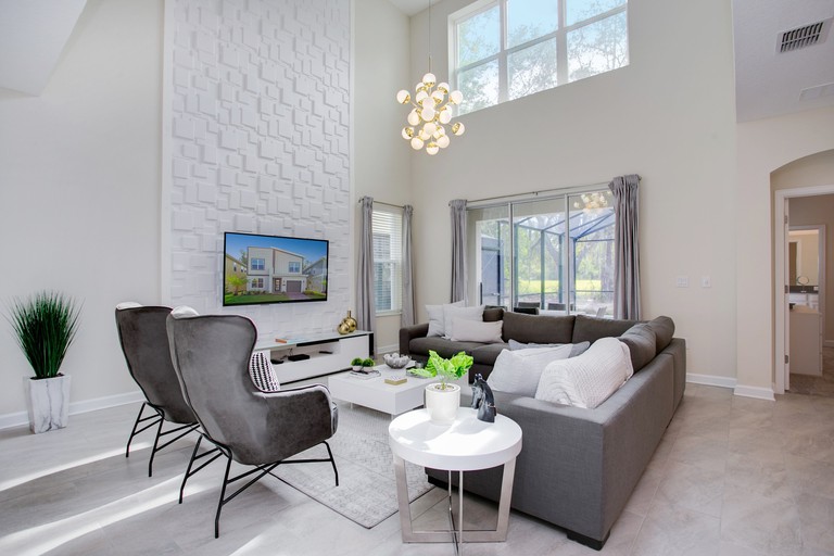 A seating area with high ceilings, white walls and gray furnishings inside Bookmark Villa Storey Lake 1