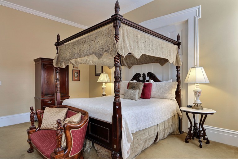 Guest room with ornate four-poster bed and antique furniture at Presidents' Quarters in Savannah