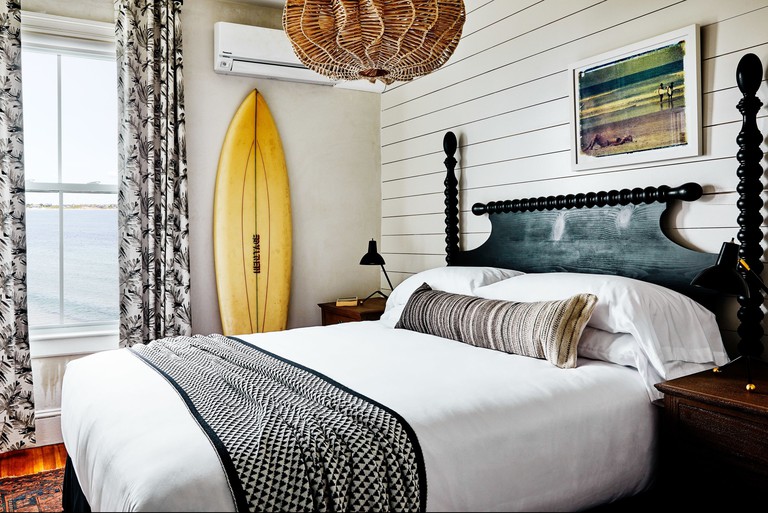Beachy chic bedroom with surfboard and ocean view at Block Island Beach House in Rhode Island