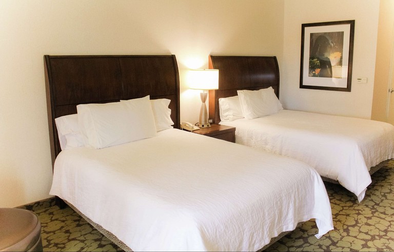Two double beds with wooden headboards in a room with a patterned carpet at Hilton Garden Inn Redding