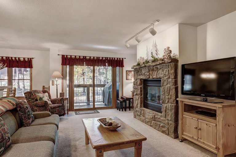 A cozy and rustic living room leading to a balcony at the Los Pinos by Breckenridge Resort Managers