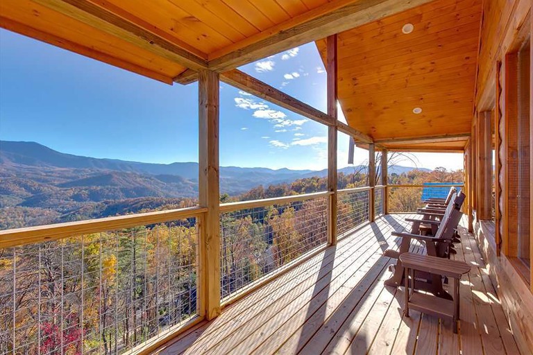 Long balcony with wooden chairs overlooking the Great Smoky Mountains at Great Smoky Lodge