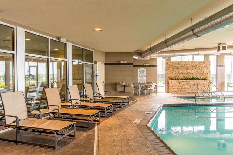 The indoor pool area at Cambria Hotel Rapid City Near Mount Rushmore, with loungers and handrails