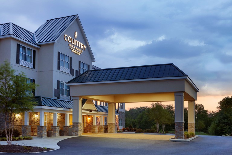 The exterior of Country Inn & Suites by Radisson, Ashland at dusk, including a covered for guests to be dropped off and picked up