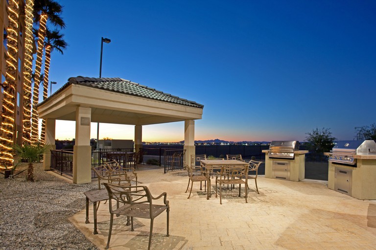 Outdoor barbecue area with two large grills and tables overlooking desert landscape at Candlewood Suites Yuma, an IHG Hotel