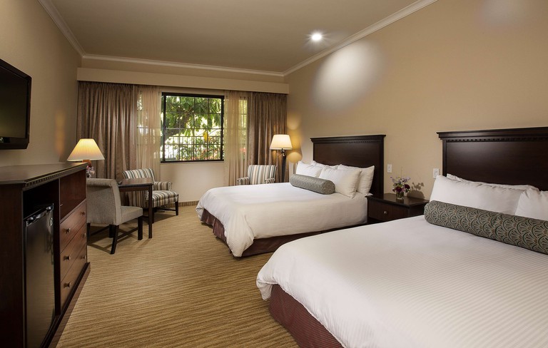 Two beds in a twin room featuring dark-wood furniture at Coast Anabelle Hotel