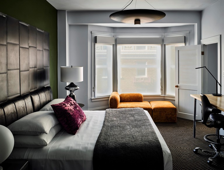 Upscale room with leather headboard, orange velvet chair, bay window and plush carpet at Hotel Zeppelin San Francisco
