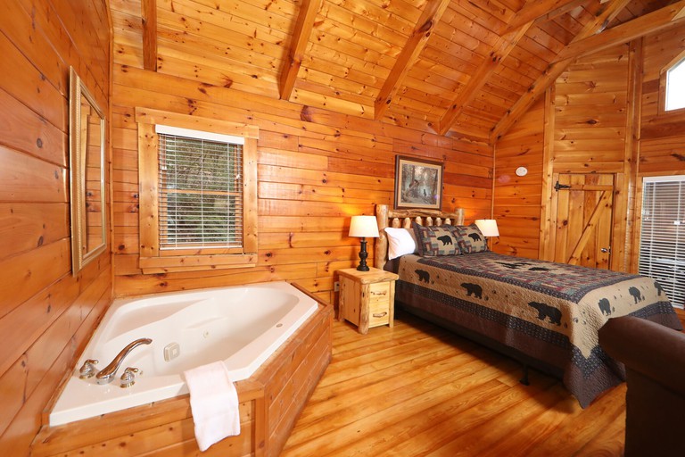 A cosy double room at the Cuddle Hut made completely of wood, with a corner bathtub in the room itself and a gabled ceiling.