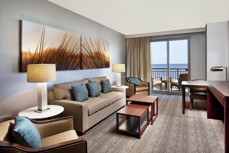 A relaxing living room, with sofa and two armchairs in a suite with ocean views from its balcony at the Westin Jekyll Island