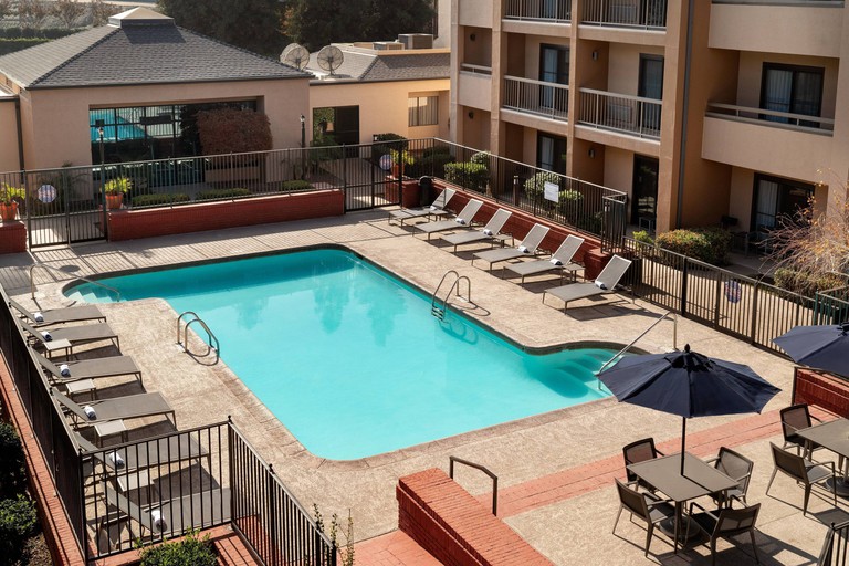 The sunny outdoor pool with loungers, tables and chairs at the Courtyard by Marriott Bakersfield