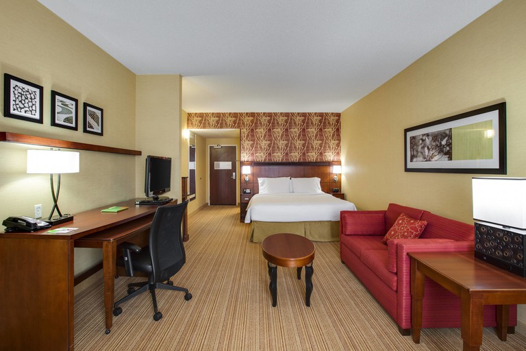 Large suite at the Courtyard Chicago Schaumburg-Woodfield Mall, with a double bed, a red sofa and a brown desk