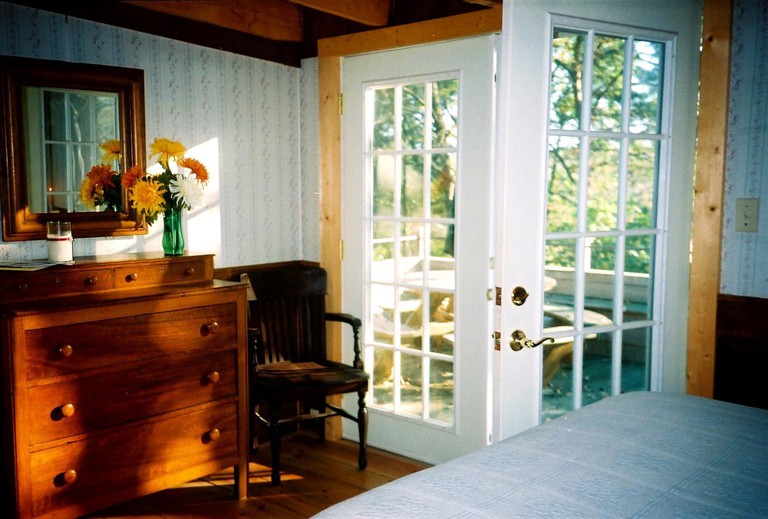 Charming bedroom with large dresser and wood floors with French doors to deck at DeHart Cabin in Lexington, Virginia