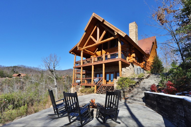 Three wooden chairs around a fire pit and wooden exterior of The Lodge at Gatlinburg