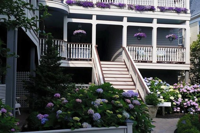 The exterior of Hydrangea House Inn, with flowers surrounding the wooden-stepped entrance