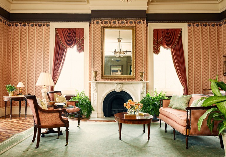 Sitting room at John Rutledge House Inn in elegant, luxurious style with orange wall carvings, fireplace and vintage furniture