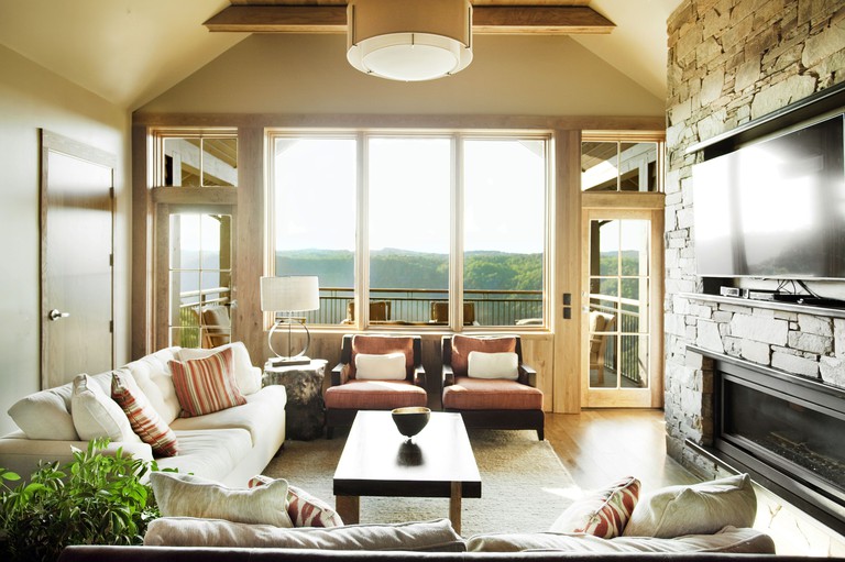 Rustic-luxe living room with stone fireplace, flat-screen TV and deck overlooking greenery at Primland Resort in Virginia