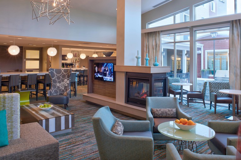 A large reception area at Residence Inn by Marriott Chicago Bolingbrook featuring chairs, tables, a television and a fireplace