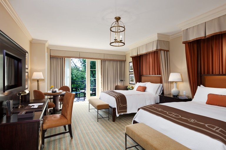 Deluxe room with two beds, plush carpet and a door to a balcony overlooking greenery at Salamander Resort