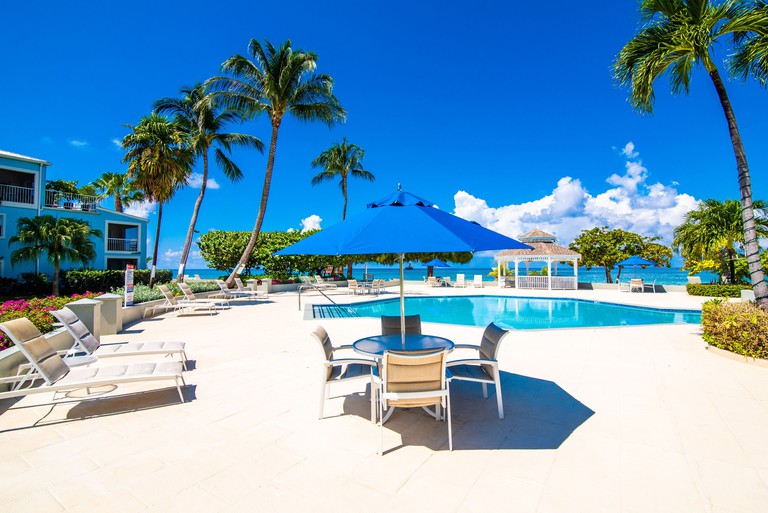 An oceanfront pool surrounded by lounge chairs and tables at the Grandview Condos on Seven Mile Beach.