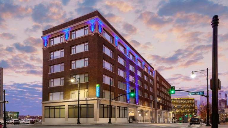 Exterior of the Holiday Inn Kansas City at dusk, showing the six-storey red-brick building and the streets nearby