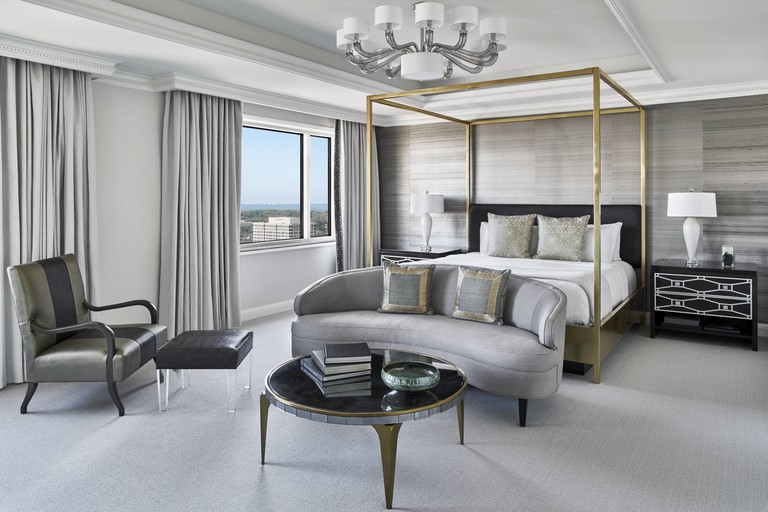 Large luxury room in silver hues with brass four-poster bed and recessed ceiling at the Ritz-Carlton Tysons Corner, Virginia