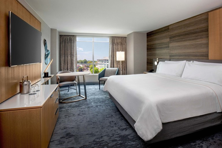 Double room at the Westin Annapolis, with wood-panelled walls, gray velvety carpet, wall-mounted TV and large window.