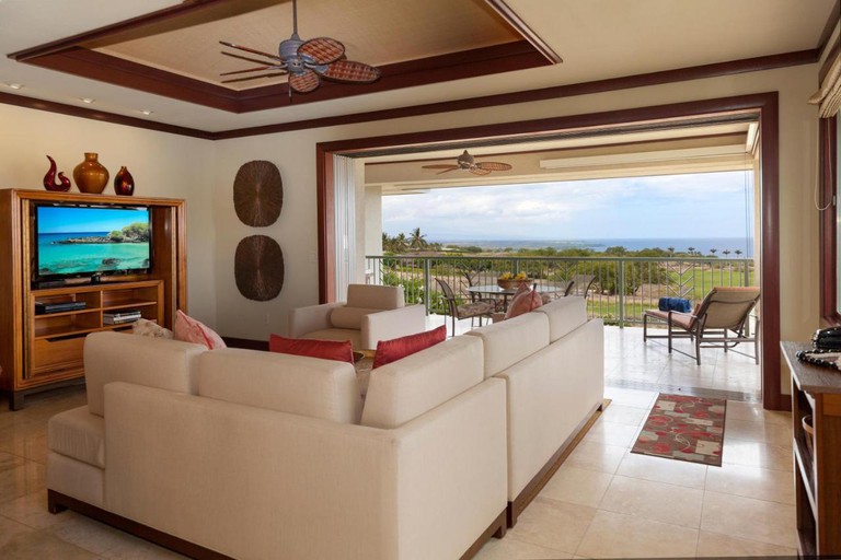 Lounge area at Wai’ula’ula, with large, cream corner sofa, opening onto a wide balcony with ocean views.