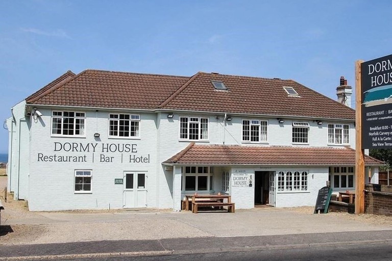 Exterior of pale blue building with pub tables in front at Dormy House in the Cotswolds