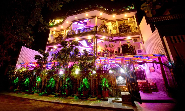 Exterior of Aman Homestay in Agra, India, lit up with multi-coloured lights illuminating every surface and floor