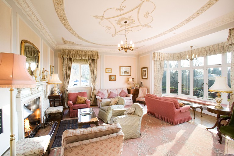 The old-world living room at Lindeth Fell Country House with a roaring fireplace, vintage sofas and a chandelier