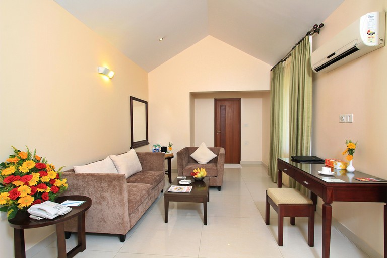 Sofa, soft chair, two tables, desk and a stool in private living space at Silent Shores Resort, Spa & Convention Centre