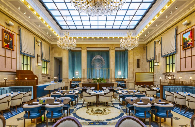 A grand restaurant with chandeliers, tables and chairs at the Langham Boston