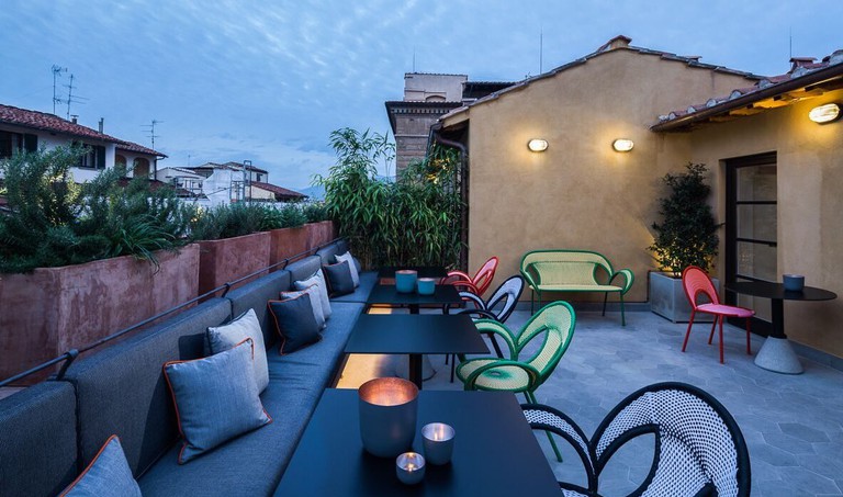 Terrace at Milu Hotel with plants, tile floors, funky furniture and ambient lighting at dusk