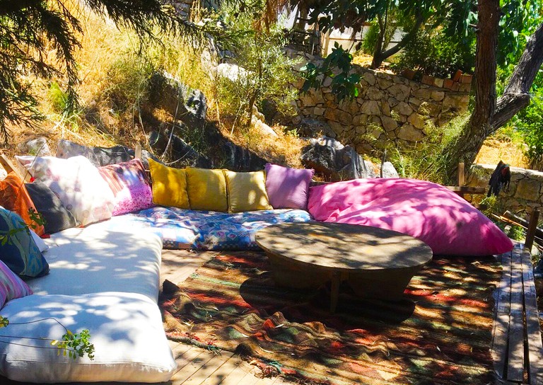 An outdoor seating area with colourful cushions surrounded by trees at Çeyrek Camping and Bungalows Patara