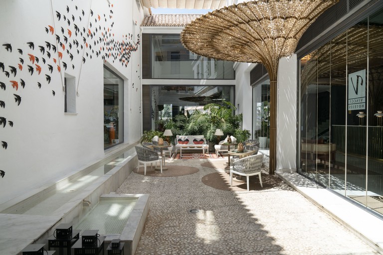 An outdoor seating area at Hotel Vincci Selección Posada del Patio with bird wall art, plants, seats and a water feature